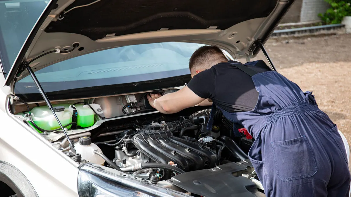 Mécanicien en bleu de travail réparant un moteur en extérieur